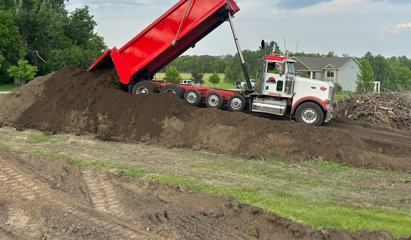 Dump truck spreading fill at a pad site
