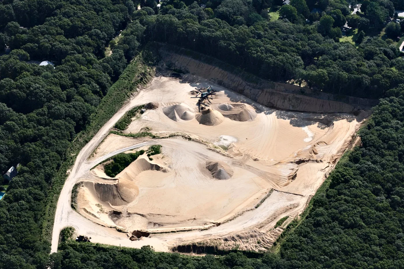 Aerial view of a working sand and dirt pit surrounded by trees