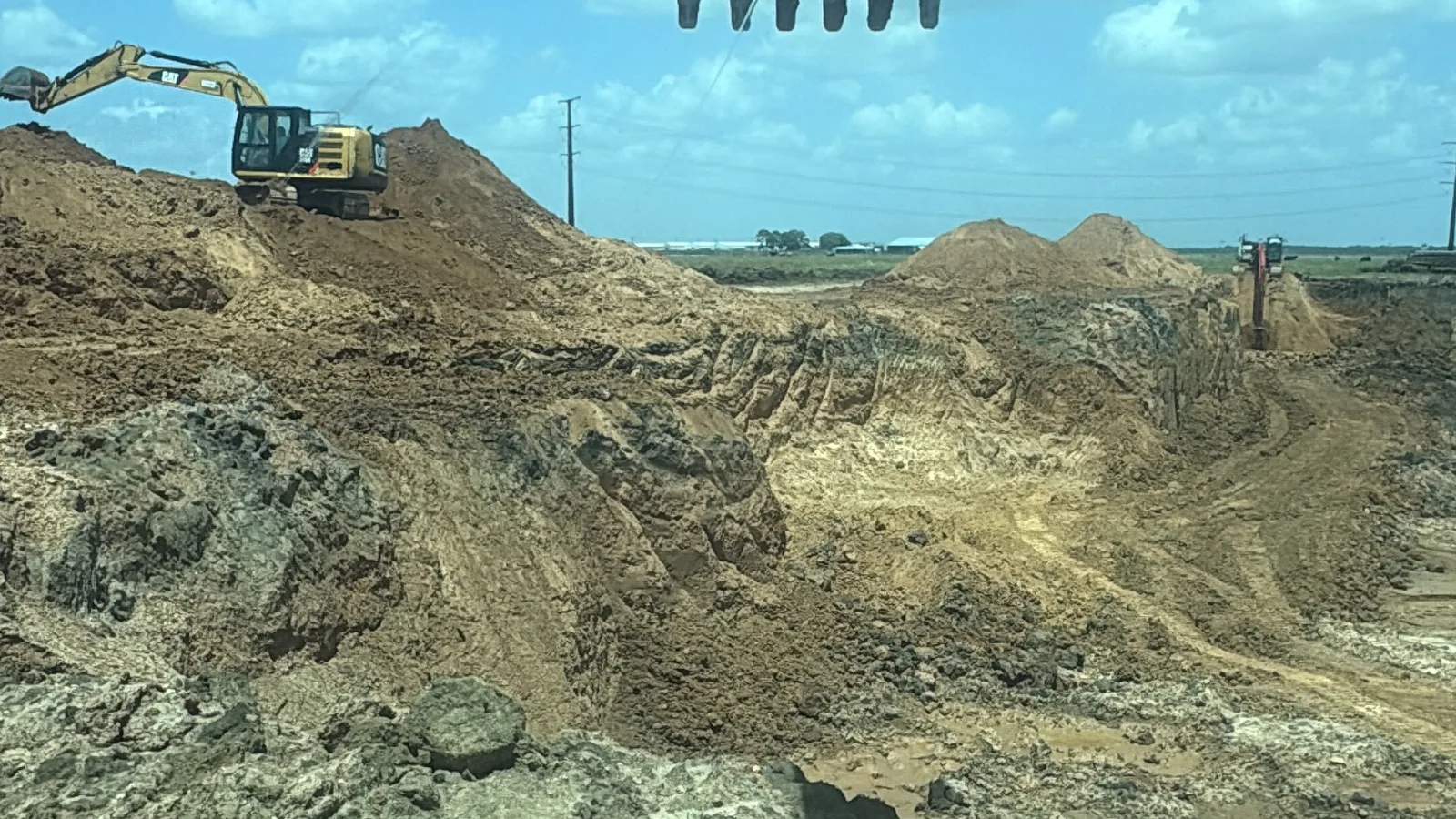 Excavators working sand and select fill stockpiles at an RLS pit in southeast Fort Bend County